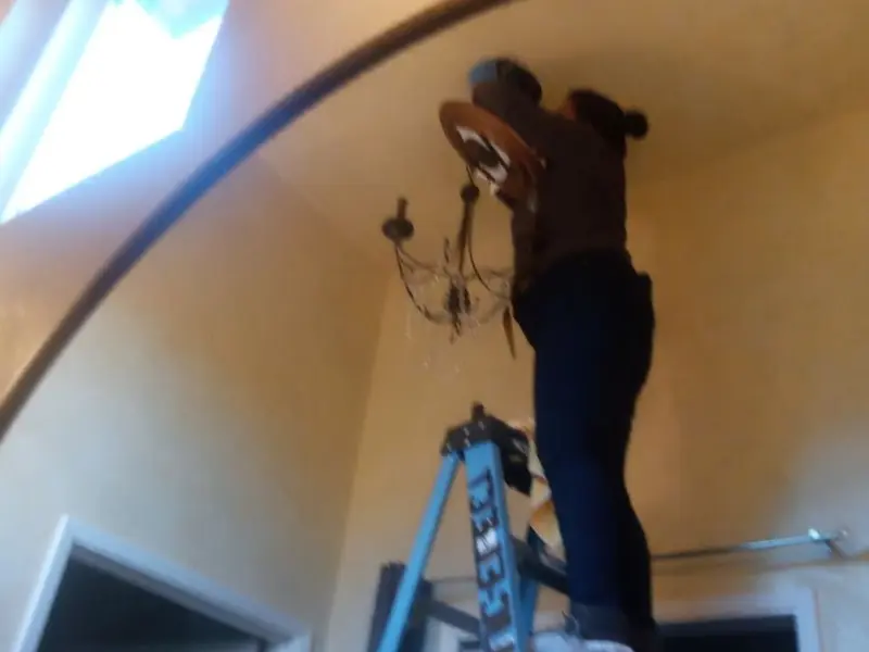 Electrician installing a chandelier in a Sierra Madre residence